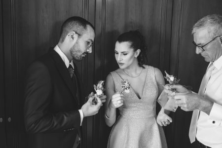 Em Santa Maria da Feira, noivos e padrinho seguram boutonnières antes da cerimónia, fotografia de casamento por Humberto Barbosa