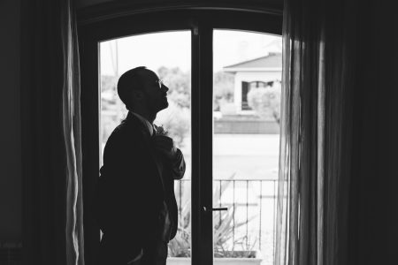 Noivo de fato aguarda em silhueta junto à varanda, fotografia de casamento por Humberto Barbosa em Santa Maria da Feira