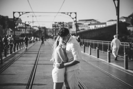 Casal apaixonado abraçado na Ponte Luís I, riso cúmplice e espontâneo captado por Humberto Barbosa, fotógrafo de casamento Porto