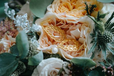 Alianças de ouro sobre pétalas de rosa em bouquet de noiva, fotografia de casamento por Humberto Barbosa em Santa Maria da Feira