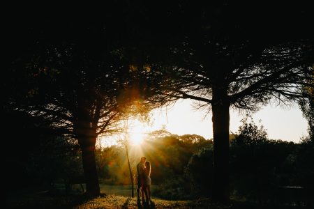 Casal abraçado entre árvores ao pôr do sol, luz dourada a envolvê-los num momento de cumplicidade — sessão pré-casamento por Humberto Barbosa, fotógrafo de casamento Porto