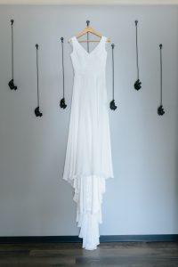 Vestido de noiva suspenso em cabide diante de parede com ganchos decorativos, fotografia de casamento por Humberto Barbosa em Santa Maria da Feira
