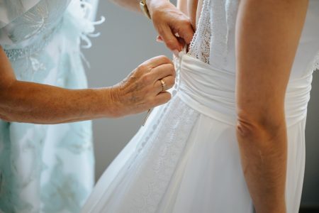 Em Santa Maria da Feira, mãos ajustam o laço do vestido da noiva antes da cerimónia, fotografia de casamento por Humberto Barbosa