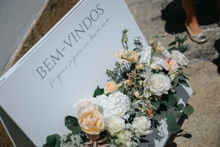 Placa de boas-vindas com flores em tons pastel capta o início da celebração, por Humberto Barbosa, fotógrafo de casamento em Santa Maria da Feira