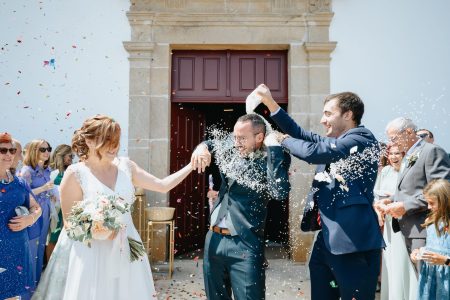 Noivos surpreendidos por arroz à saída da igreja captados por Humberto Barbosa, fotógrafo de casamento em Santa Maria da Feira