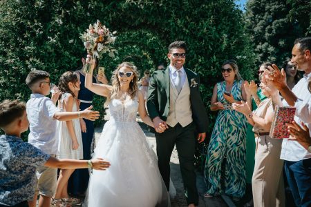 fotografo de Casamento Santa Maria da Feira, humberto barbosa fotografia de Casamento Porto, Quinta da Quintã Quinta de Casamento Pé de Flor Music beats Noivos felizes saem de mãos dadas entre aplausos dos convidados, ela ergue o bouquet em celebração — fotógrafo de casamento Santa Maria da Feira, Humberto Barbosa Fotografia