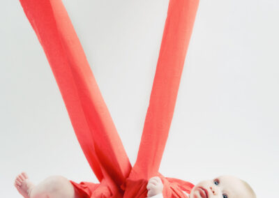Recém-nascido envolto em tecido coral vermelho captado por Humberto Barbosa em São João da Madeira — fotografia newborn criativa