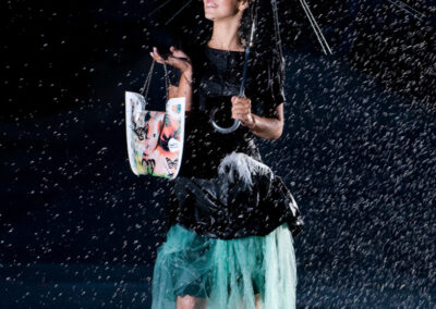 Modelo sob chuva artificial com guarda-chuva e saia turquesa captada por Humberto Barbosa em Porto — fotografia de moda criativa